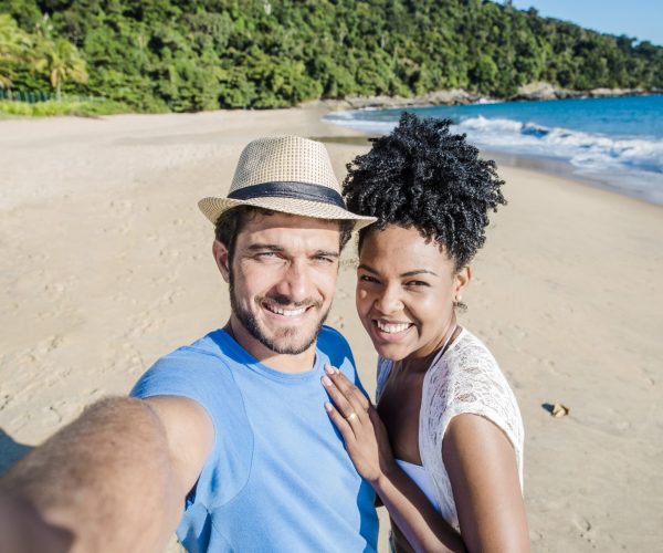 pareja-sonriente-haciendo-selfie-playa-min